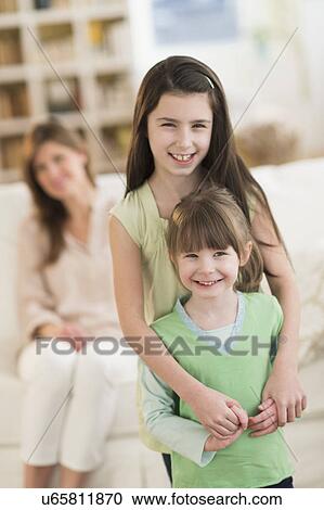 Stock Image - Mother and daughters (4-5, 8-9) at home. Fotosearch