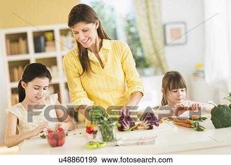 Mother and daughters (4-5, 8-9) cooking in kitchen View Large Photo Image Stock Photo - Mother and daughters (4-5, 8-9) cooking in kitchen. Fotosearch