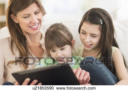 Stock Image - Mother and daughters (4-5, 8-9) using tablet pc. Fotosearch
