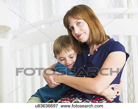 Stock Photo - Mother embracing son (8-9). Fotosearch