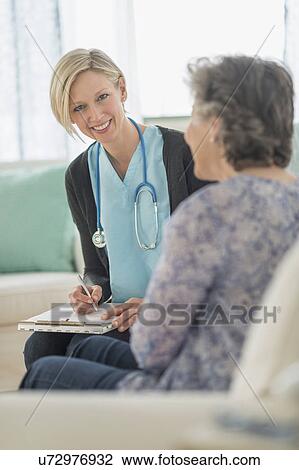 Nurse and mature woman sitting on sofa View Large Photo Image Stock Image - Nurse and mature woman sitting on sofa. Fotosearch