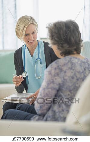 Nurse and mature woman sitting on sofa View Large Photo Image Stock Photo - Nurse and mature woman sitting on sofa. Fotosearch