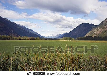Pasture surrounded by mountains View Large Photo Image Stock Photography - Pasture surrounded by mountains. Fotosearch