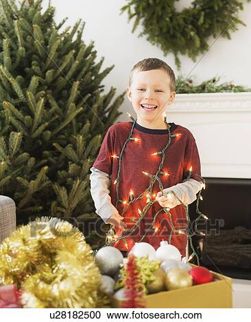 Portrait of boy (6-7) holding Christmas lights View Large Photo Image Stock Image - Portrait of boy (6-7) holding Christmas lights. Fotosearch