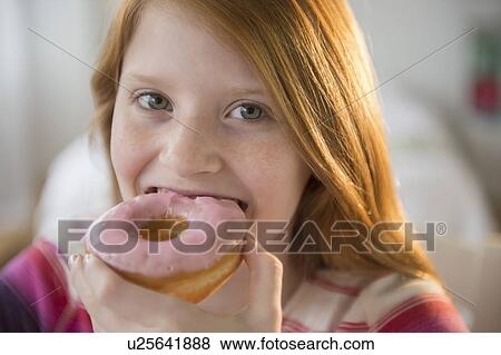 Portrait of girl (12-13) eating doughnut View Large Photo Image Stock Photo - Portrait of girl (12-13) eating doughnut. Fotosearch