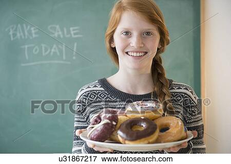 Portrait of girl (12-13) holding plate with doughnut View Large Photo Image Stock Photo - Portrait of girl (12-13) holding plate with doughnut. Fotosearch
