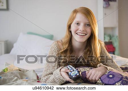 Stock Image - Portrait of girl (12-13) lying on bed. Fotosearch