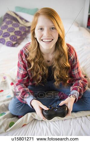 Stock Image - Portrait of girl (12-13) playing video games. Fotosearch