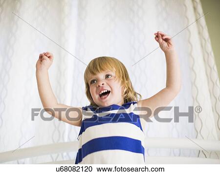 Stock Image - Portrait of girl (4-5) with arms raised. Fotosearch