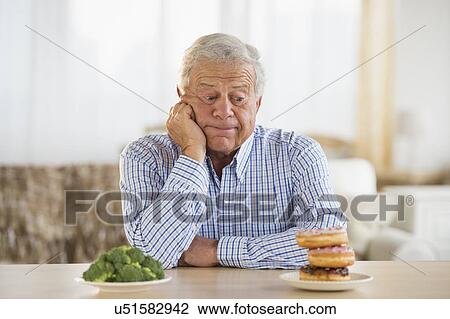 Portrait of senior man looking at doughnut View Large Photo Image Stock Image - Portrait of senior man looking at doughnut. Fotosearch