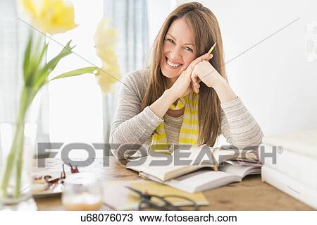 Portrait of smiling woman sitting at desk View Large Photo Image Stock Image - Portrait of smiling woman sitting at desk. Fotosearch