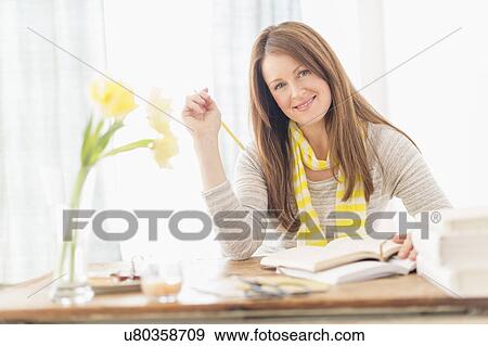 Portrait of smiling woman sitting at desk View Large Photo Image Stock Photo - Portrait of smiling woman sitting at desk. Fotosearch