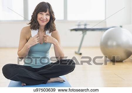 Portrait of woman sitting on mat in gym View Large Photo Image Stock Photo - Portrait of woman sitting on mat in gym. Fotosearch