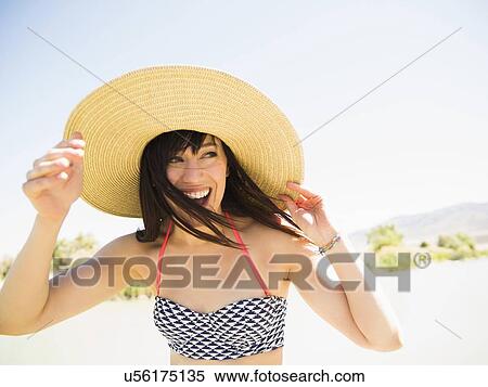 Stock Photography - Portrait of woman wearing sun hat on beach. Fotosearch