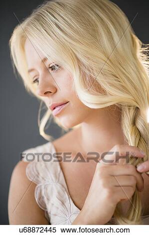 Stock Photography - Portrait of young woman braiding hair. Fotosearch
