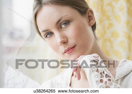 Stock Photography - Portrait of young woman by window. Fotosearch
