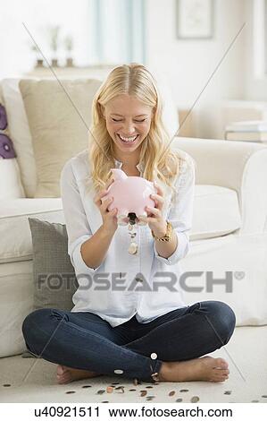 Portrait of young woman empting coins from piggy bank View Large Photo Image Stock Image - Portrait of young woman empting coins from piggy bank. Fotosearch