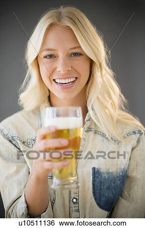 Portrait of young woman holding glass of beer View Large Photo Image Stock Photograph - Portrait of young woman holding glass of beer . Fotosearch