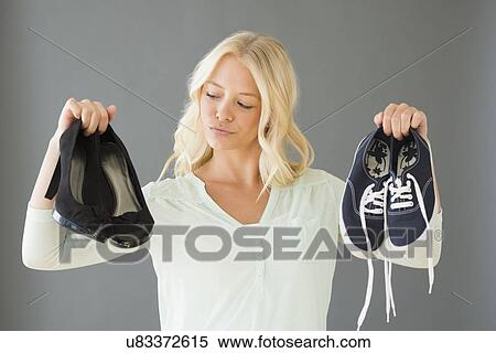 Stock Photography - Portrait of young woman holding shoes. Fotosearch