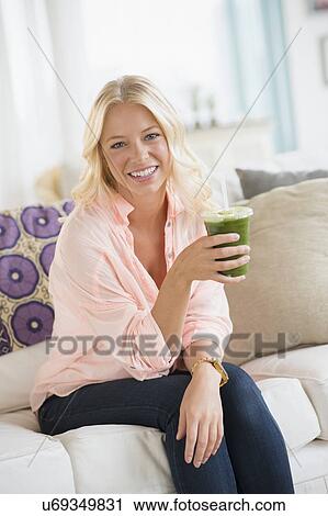 Portrait of young woman holding smoothie View Large Photo Image Stock Image - Portrait of young woman holding smoothie. Fotosearch