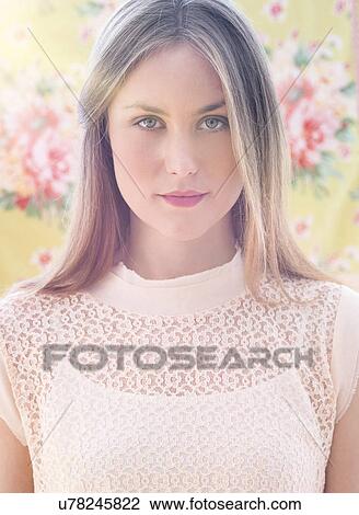 Stock Image - Portrait of young woman in front of floral wall paper. Fotosearch