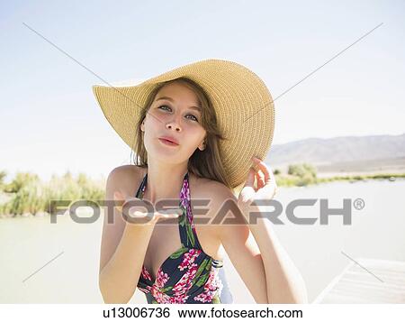 Stock Photograph - Portrait of young woman wearing sun hat on beach. Fotosearch