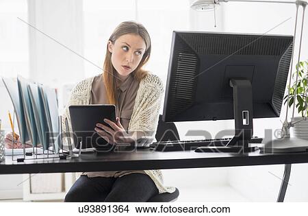 Portrait of young woman working digital tablet in office View Large Photo Image Picture - Portrait of young woman working digital tablet in office. Fotosearch