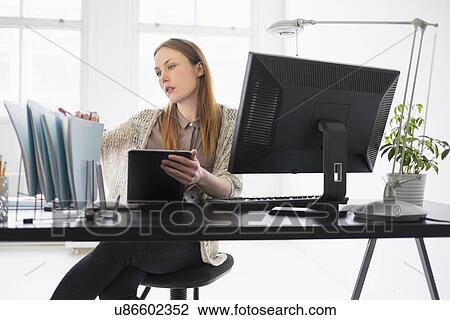 Stock Image - Portrait of young woman working in office. Fotosearch