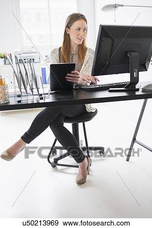 Stock Photo - Portrait of young woman working in office. Fotosearch