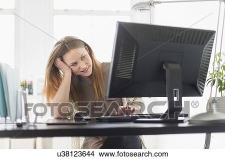 Picture - Portrait of young woman working on computer in office. Fotosearch