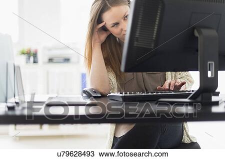 Portrait of young woman working on computer in office View Large Photo Image Stock Image - Portrait of young woman working on computer in office. Fotosearch