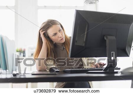 Stock Photo - Portrait of young woman working on computer in office. Fotosearch
