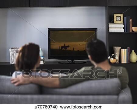 Rear view of couple watching tv View Large Photo Image Stock Image - Rear view of couple watching tv. Fotosearch