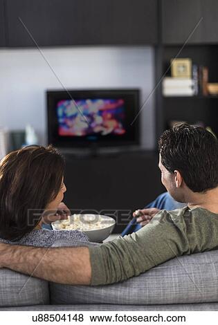 Rear view of couple watching tv View Large Photo Image Stock Photo - Rear view of couple watching tv. Fotosearch