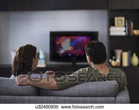 Rear view of couple watching tv View Large Photo Image Stock Photography - Rear view of couple watching tv. Fotosearch