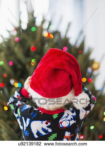 Stock Image - Rear view of kid (6-7) wearing santa hat. Fotosearch