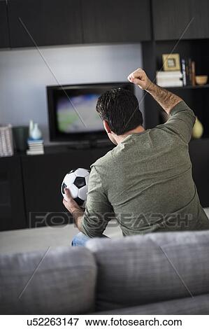 Rear view of man watching sports on tv View Large Photo Image Stock Photo - Rear view of man watching sports on tv. Fotosearch