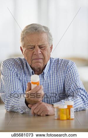 Stock Image - Senior man holding pill bottle. Fotosearch