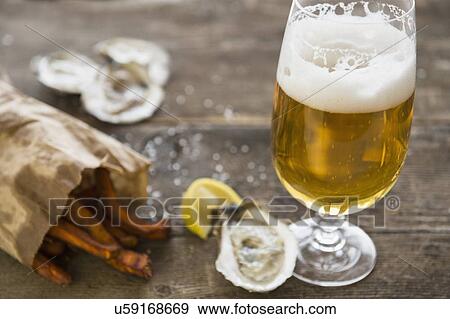 Stock Photo - Studio shot of glass of beer, oysters and french fries. Fotosearch