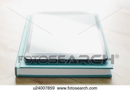 Studio shot of tablet on book View Large Photo Image Stock Photo - Studio shot of tablet on book. Fotosearch