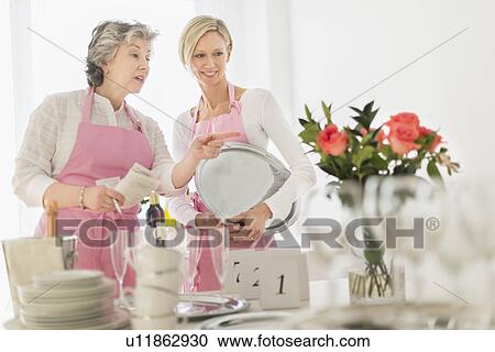 Stock Image - Two mature women preparing catering. Fotosearch