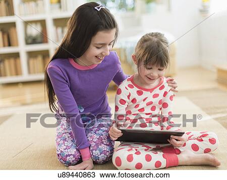 Stock Image - Two sisters (4-5, 8-9) using tablet pc. Fotosearch