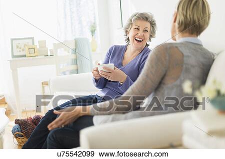 Stock Photo - Two women sitting on coach talking. Fotosearch