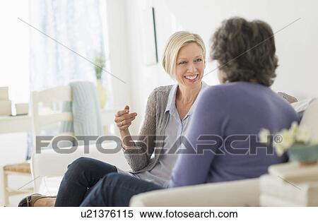 Two women sitting on coach talking View Large Photo Image Stock Photography - Two women sitting on coach talking. Fotosearch