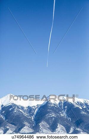 Vapor trail on clear sky above mountains View Large Photo Image Stock Photograph - Vapor trail on clear sky above mountains. Fotosearch