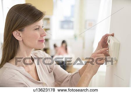 Stock Photo - Woman adjusting house alarm. Fotosearch