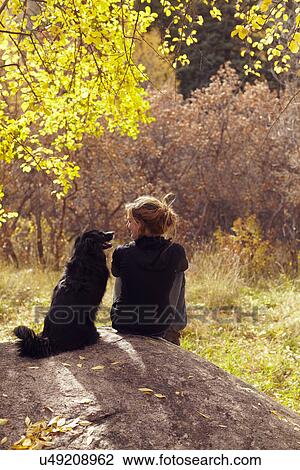 Stock Image - Woman and her collie sitting on stone. Fotosearch