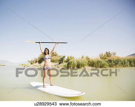 Stock Image - Woman balancing on surfboard. Fotosearch