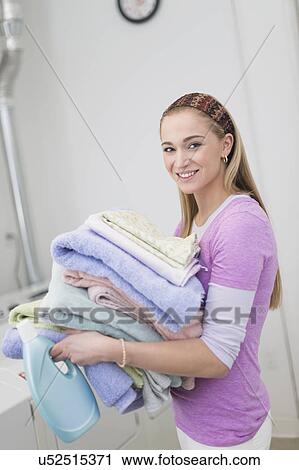 Stock Image - Woman carrying stack of clean towels. Fotosearch