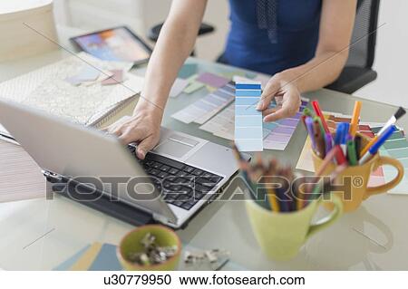 Woman holding color swatches and using laptop View Large Photo Image Stock Image - Woman holding color swatches and using laptop. Fotosearch